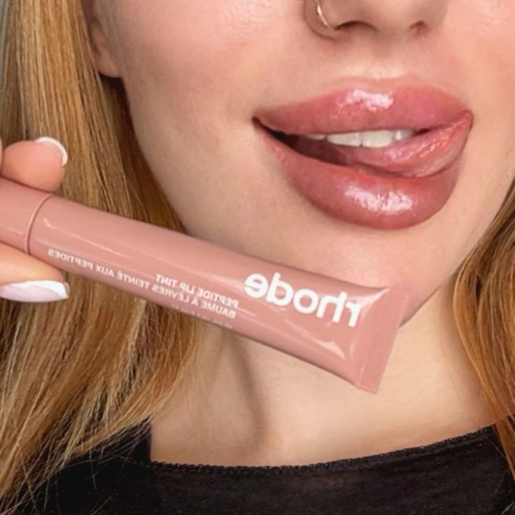 Woman applying lip gloss with a close-up of the product